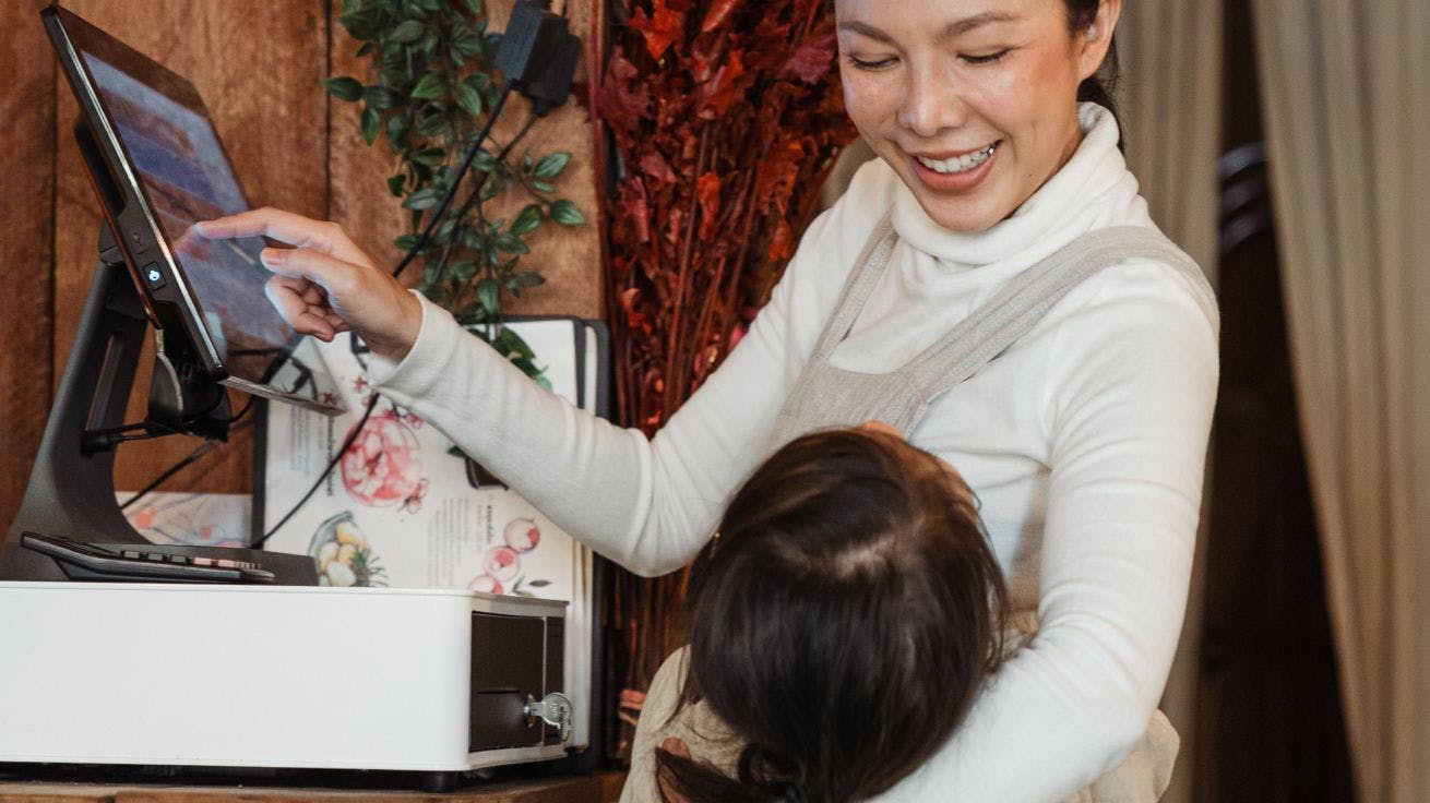 A person using a payment terminal while hugging a child