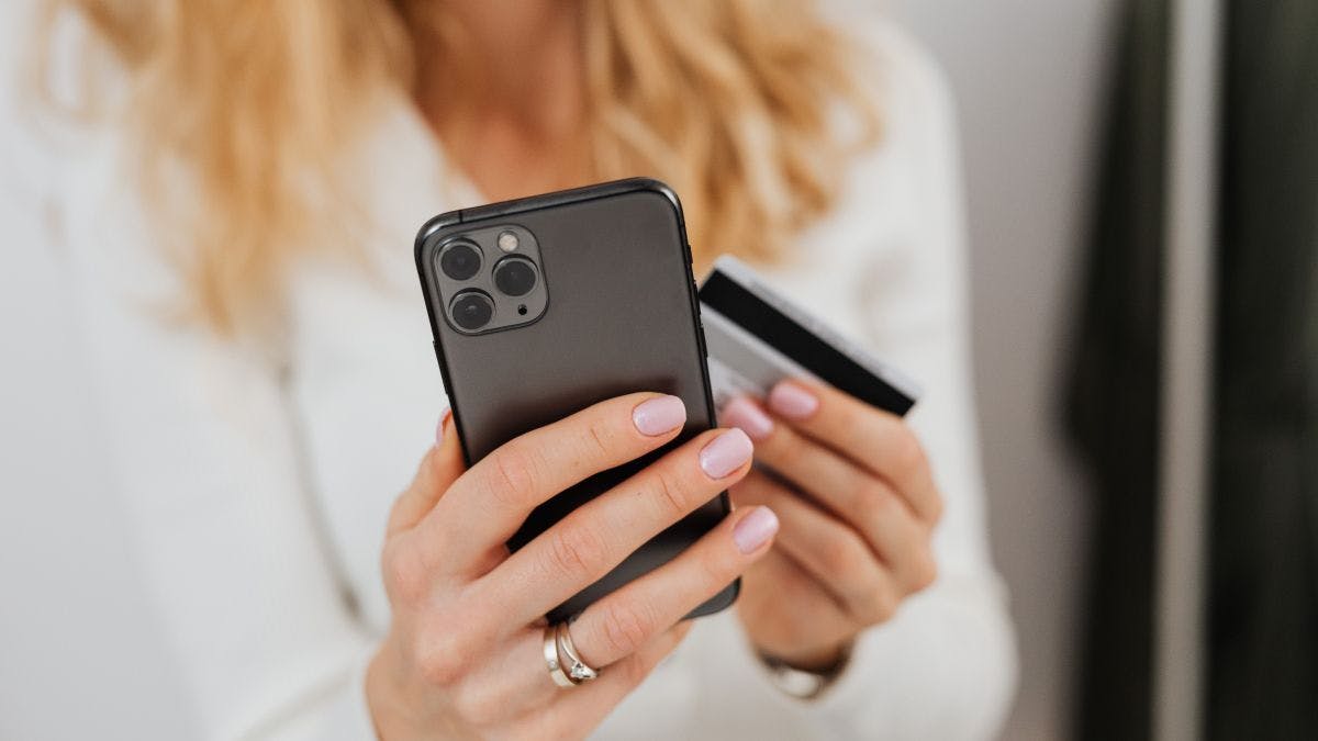 A person holding a cell phone and a credit card.