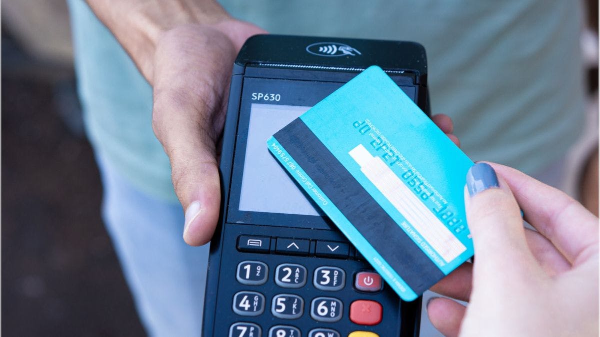 A person holding a credit card and a payment machine.