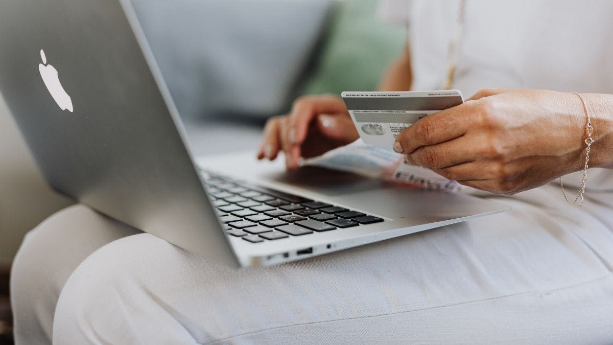 A person holding a credit card and using a laptop.
