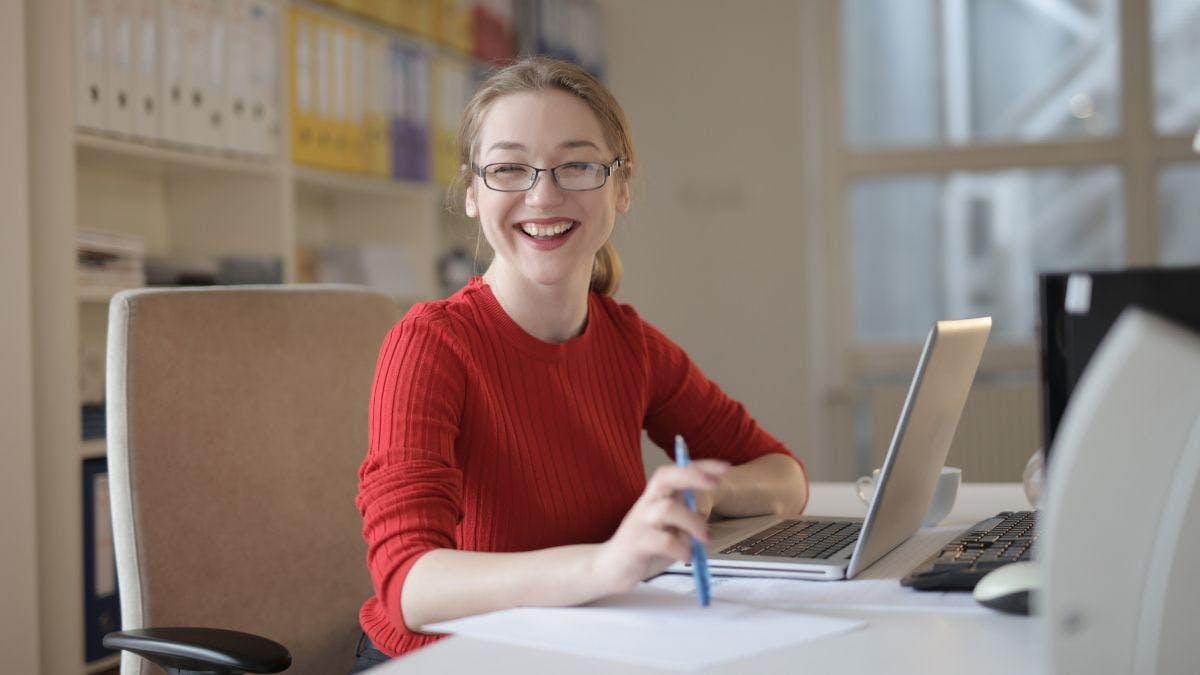 A person smiling at a laptop. 