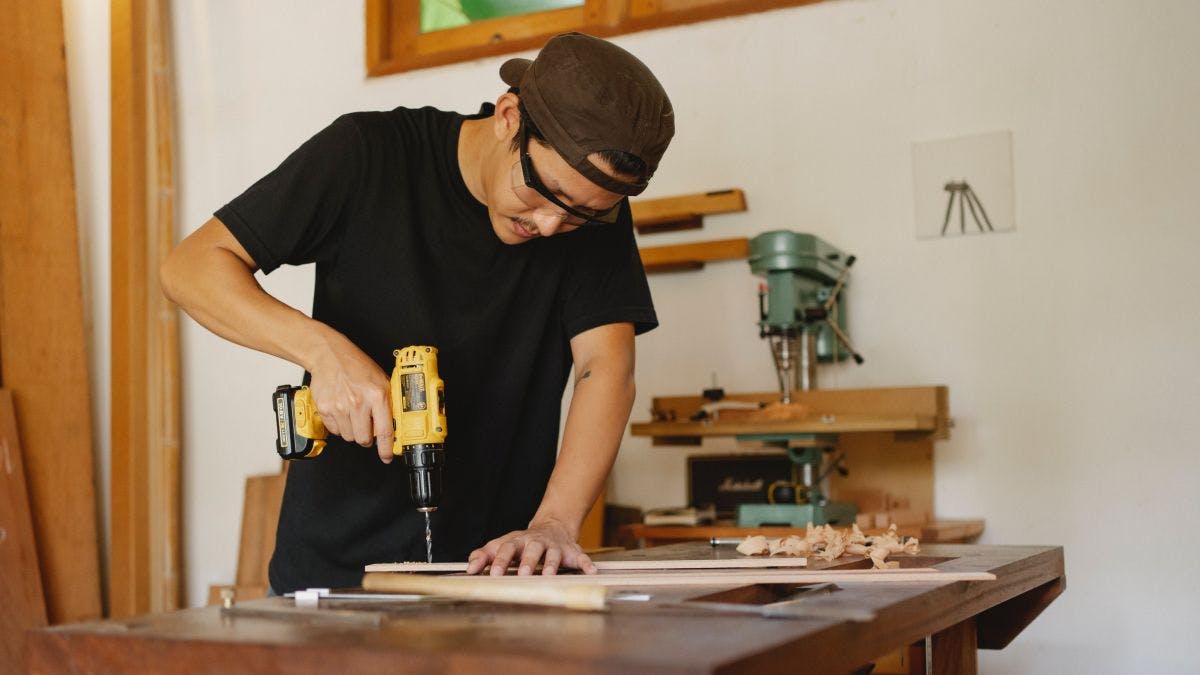 A person using a drill to drill wood.